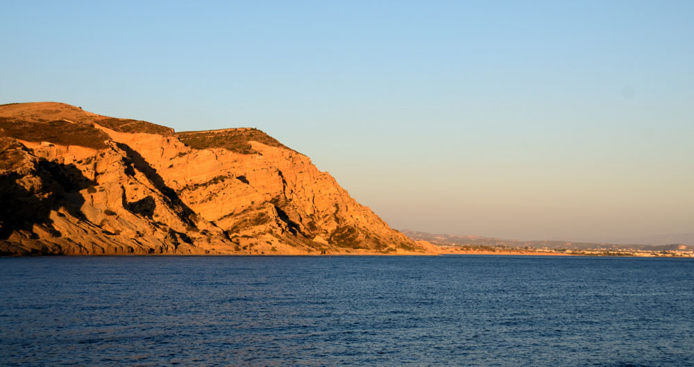 Agia Galini, am Strand bringt die Abendsonne die Felsen zum Glühen, rechts daneben die Ausläufer der Messara-Ebene.