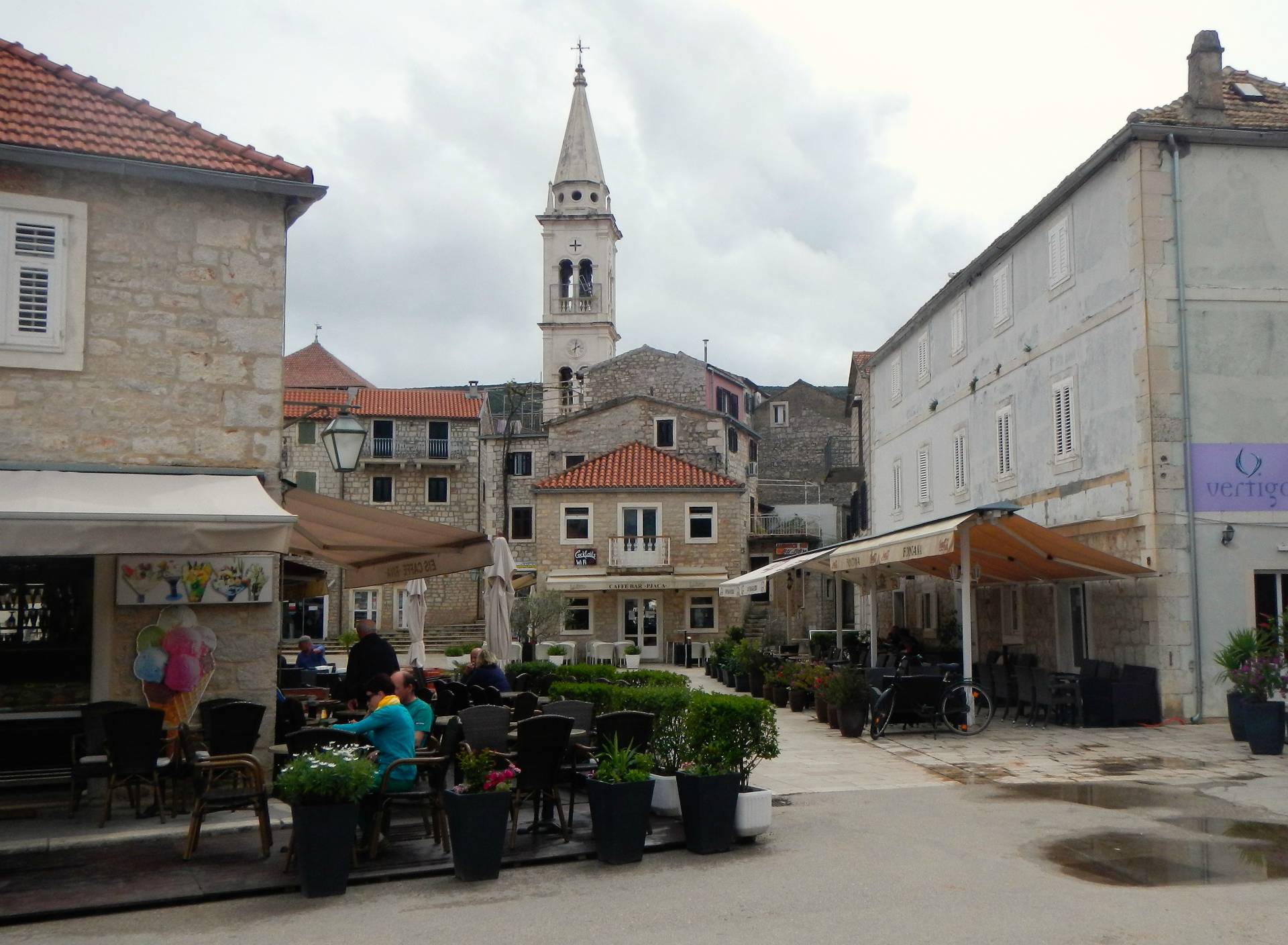 ...im Hafen von Jelsa mit dem Turm der Burgkirche Zur Hl. Maria. Der Platz der kroatischen nationalen Wiedergeburt (Pjaca). Auf der Westseite des Platzes befindet sich eine Trinkwasserquelle – Slatina – die bereits seit der Antike der Stadtbevölkerung zur Verfügung stand. In einer Verlängerung der Quelle ist 1847 ein Flüsschen geschaffen worden, das den Wasserüberschuss ins Meer abführt. Den Platzmittelpunkt ziert ein im Jahr 1934 erbauter Springbrunnen...