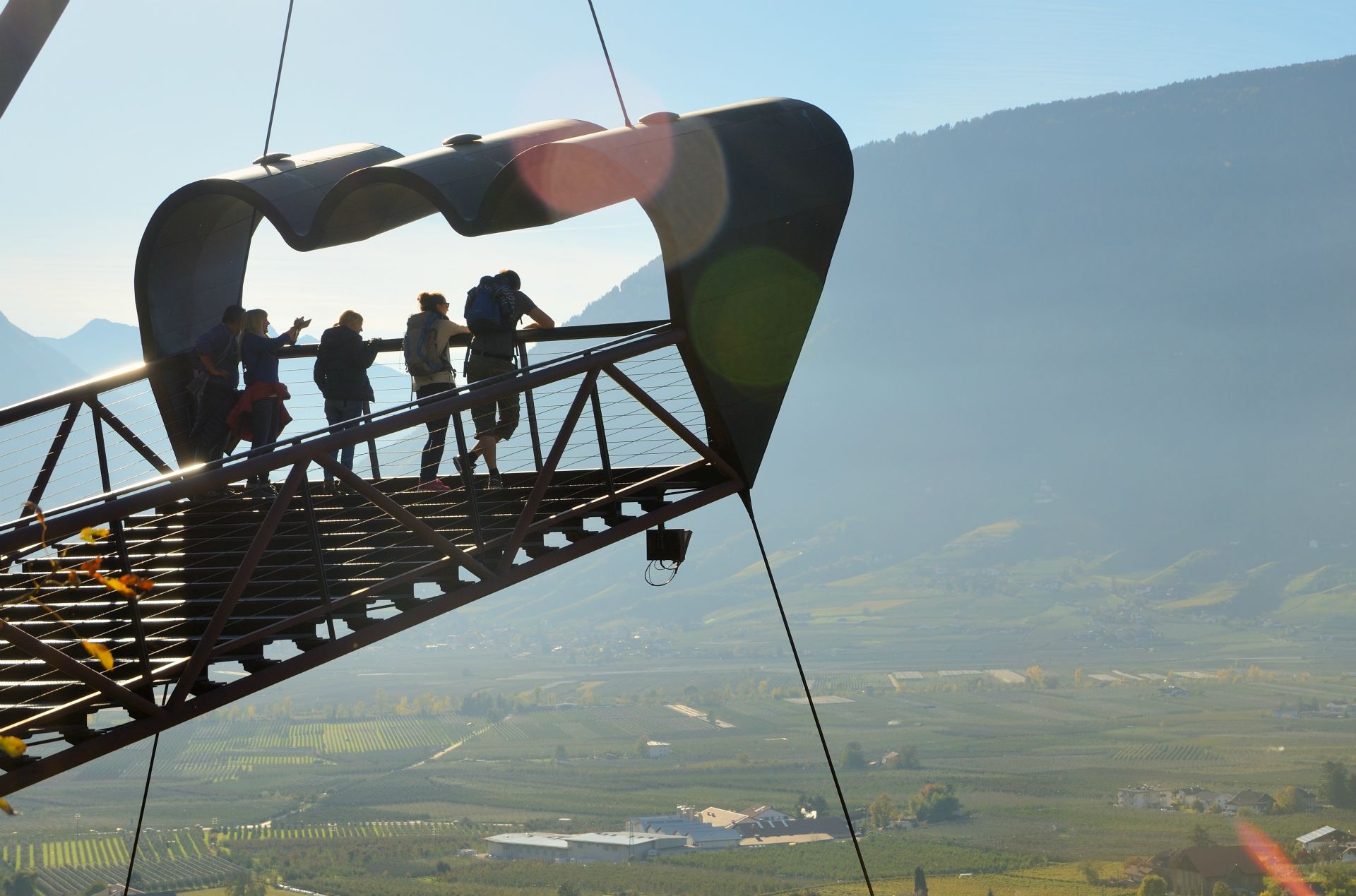 Die spektakuläre, zu 95 % sichtdurchlässige Aussichtsplattform wurde 2005 nach einer Idee des Südtiroler Architekten und Designers Matteo Thun realisiert: Über Stufen „schweben“ die BesucherInnen nach oben in Richtung Himmel. Wie durch einen überdimensionalen Gucker, ein Fernrohr, genießen sie eine atemberaubende Aussicht auf das Etschtal, den Meraner Talkessel und die umliegende Bergwelt.